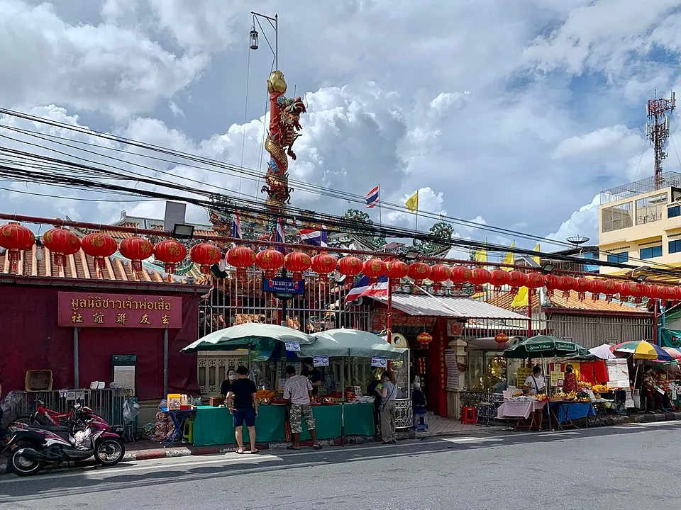 บริเวณหน้าทางเข้าศาลเจ้าพ่อเสือ โดยกำแพงวัดจะเป็นสีแดงและมีเสาสูงที่มีมังกรพันรอบเสาตั้งขึ้นอยู่ภายในวัด ซึ่งหน้าลานวัดมีร้านขายดอกไม้และของไหว้ตั้งขายอยู่ และมีผู้คนกำลังซื้อขายกันอยู่